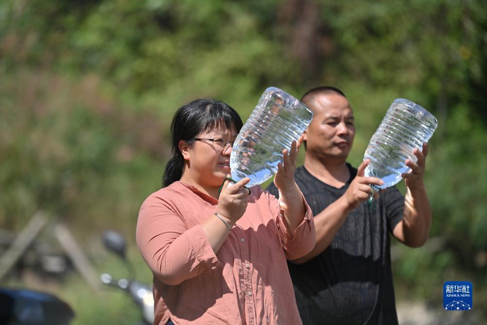 楊寧（左）在查看村民剛剛采集的水樣，為山泉水引水工程做準(zhǔn)備（10月8日攝）。新華社記者 黃孝邦 攝